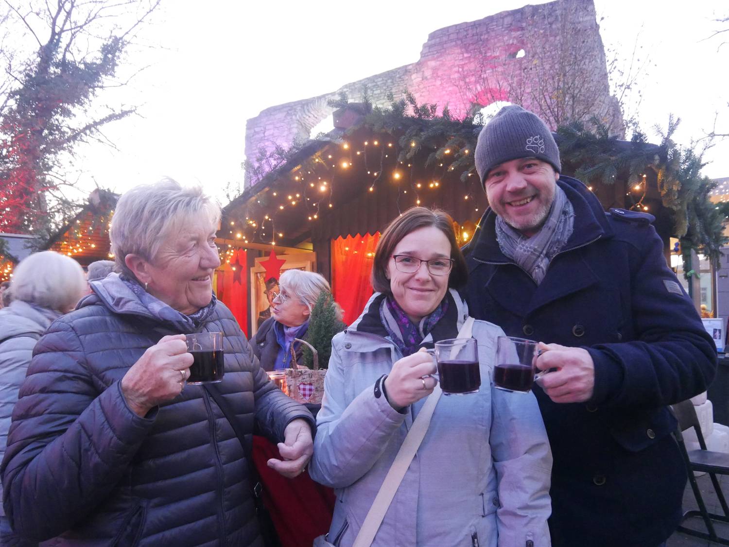 Bildzeile: Stoßen auf einen gelungenen Weihnachtsmarkt in Bad Lippspringe an: Anke, unsere Königin Nadine und unser König  Frank Täubert. Die Burgruine verleiht dem Weihnachtsmarkt  das  besondere  Flair.  Foto: Klaus Karenfeld